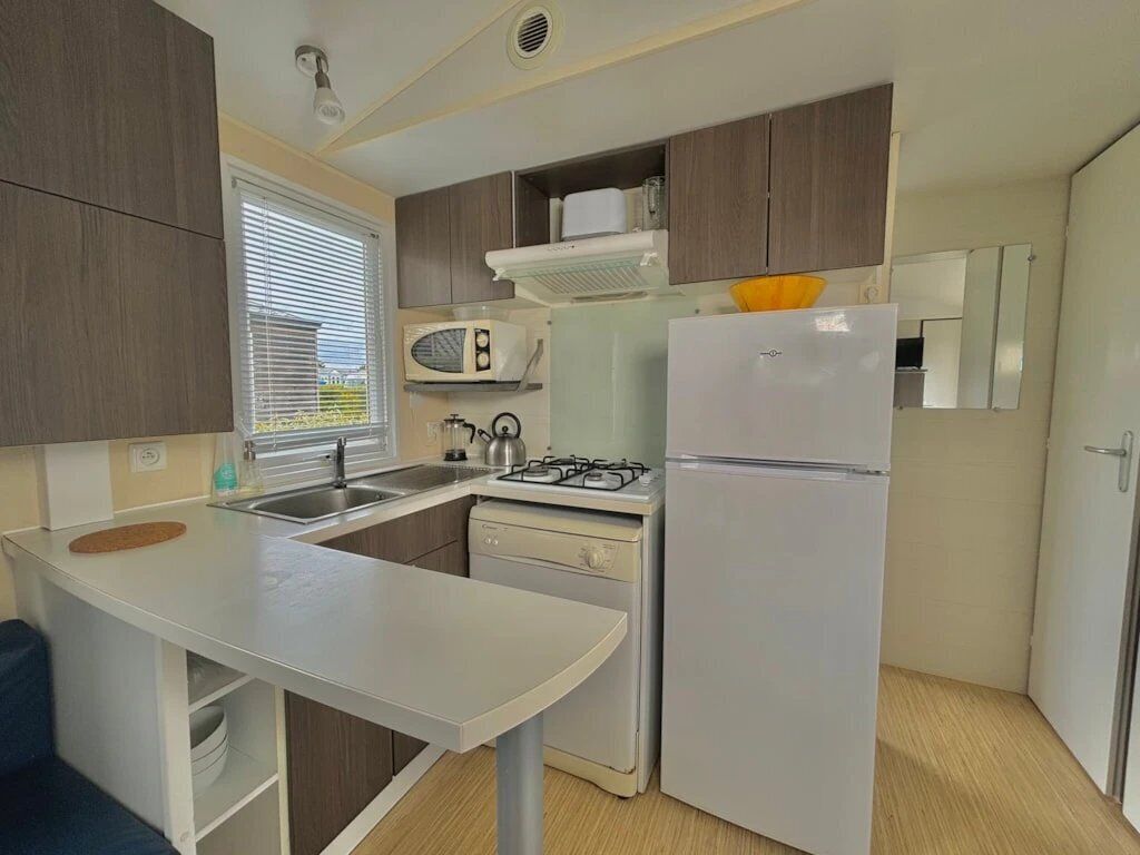 Cocina compacta con estufa a gas, microondas y refrigerador.