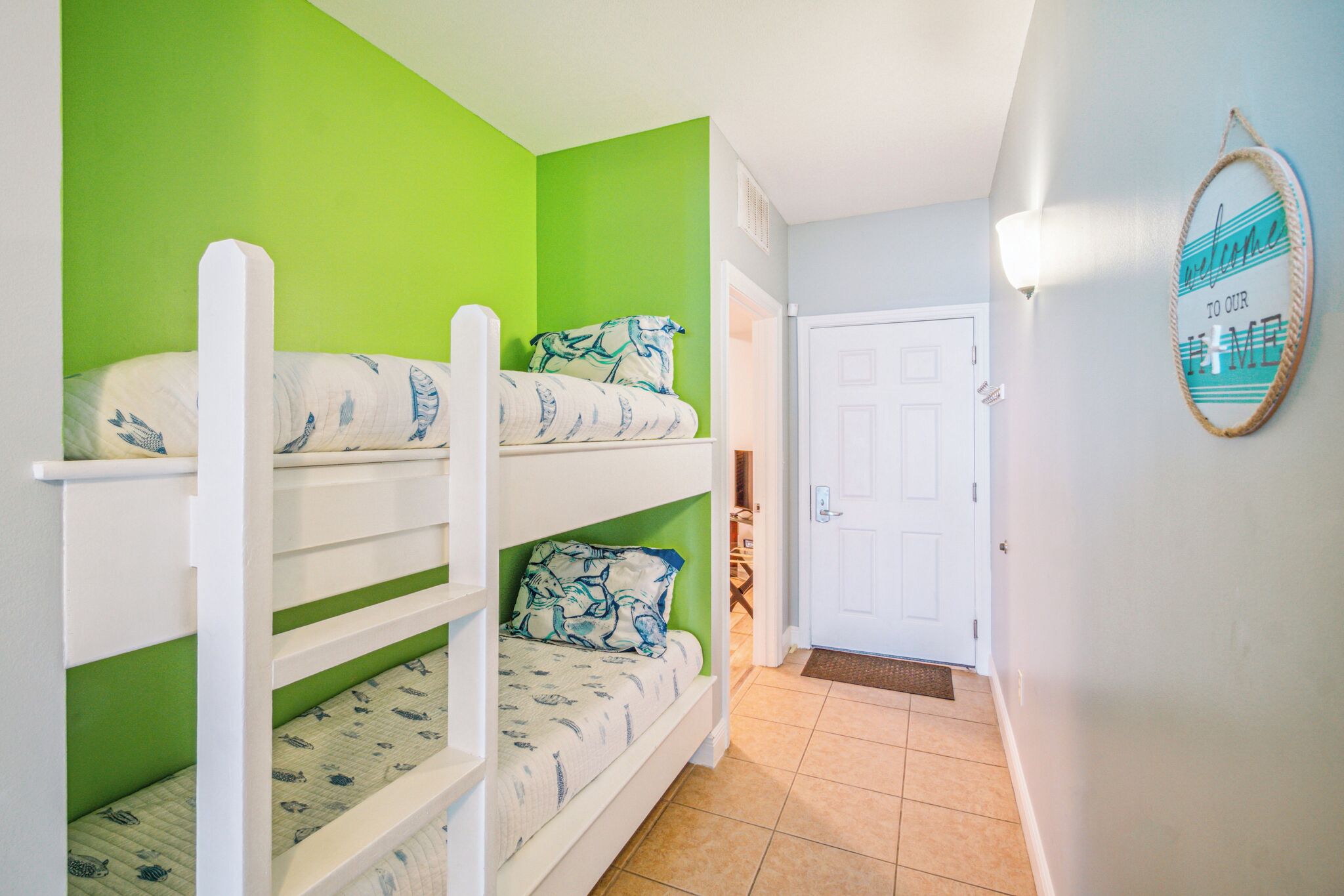A room with bunk beds, a door, and a welcome sign.