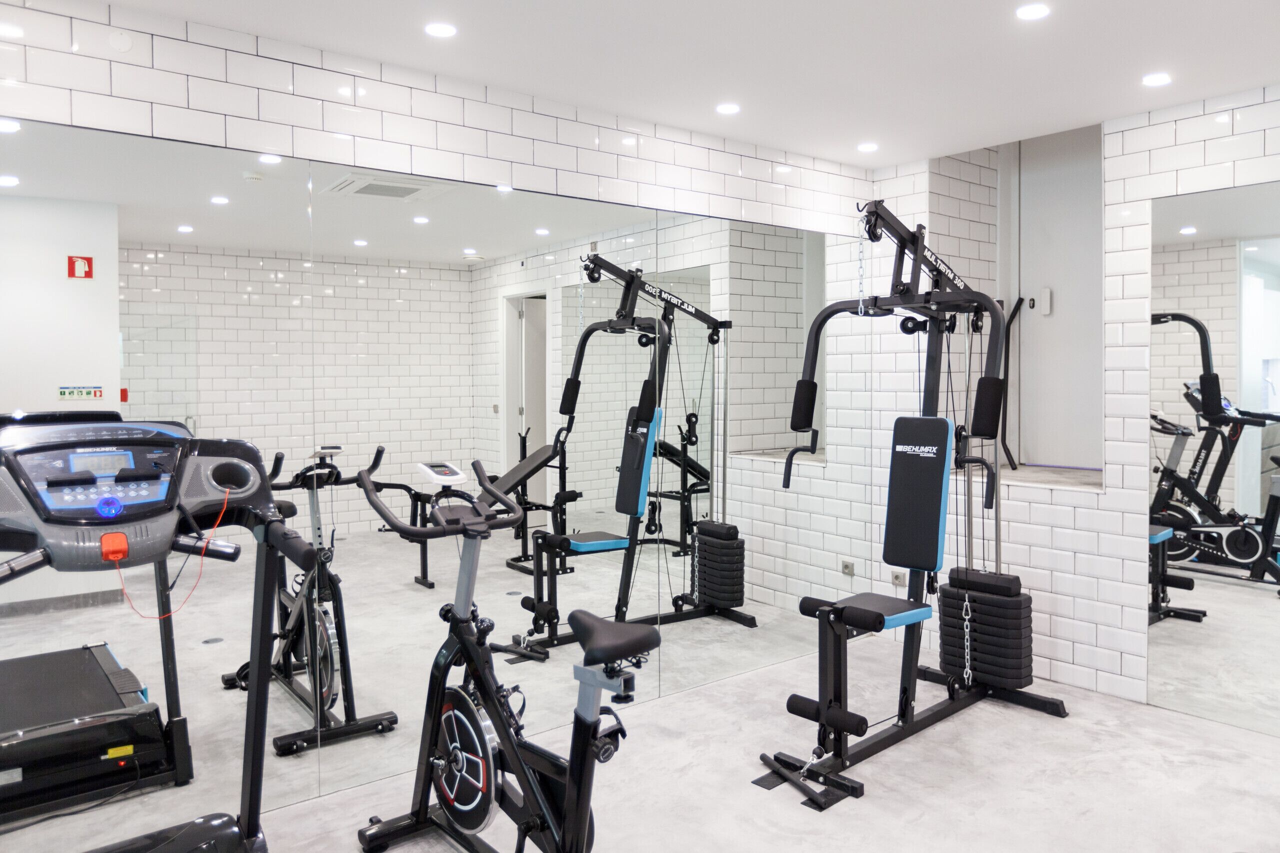 Un gimnasio con diversos equipos de ejercicio, incluyendo cintas de correr, bicicletas estáticas y máquinas de pesas.
