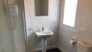 A bathroom with a shower, sink, toilet, and a mirror. - Railway Inn (Buckhaven)