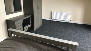 A bedroom with a bed, a wardrobe, a TV, and a radiator. - Railway Inn (Buckhaven)