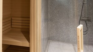 Un sauna en bois avec une porte en verre, un espace douche avec un mur en marbre et un petit banc en bois.