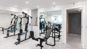 Une salle de sport moderne équipée de divers appareils d’exercice, dotée de murs recouverts de miroirs et d’un sol carrelé et impeccable.