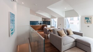 A modern living room with a grey sofa, a glass coffee table, and a dining area with a round table and chairs. - FLH Glória 70  Duplex I (Lisbon)