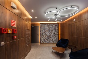 Eine moderne Lobby mit Holzwandverkleidung, einer Wand mit Weltkartenmuster, einer hölzernen Bank und einem blauen Sessel.