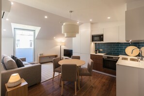 Une cuisine moderne avec un coin repas, un plancher en bois et une grande fenêtre.