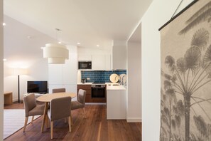 Une cuisine moderne avec un mur de crédence bleu, un coin repas avec une table ronde et des chaises, et une grande œuvre d’art accrochée au mur.