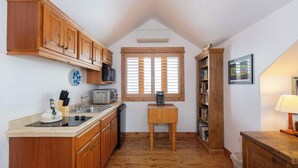 A kitchen with wooden cabinets, a microwave, a toaster, and a window with blinds. - Welcome to Hyalite Loft - Fully Furnished Loft Near Hyalite (Bozeman)