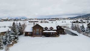 A large wooden lodge with a snow-covered roof, surrounded by snow-covered trees and mountains in the background. - Welcome to Hyalite Loft - Fully Furnished Loft Near Hyalite (Bozeman)