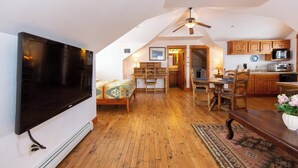 A spacious loft with a large TV, wooden floors, a dining area, and a kitchen with wooden cabinets. - Welcome to Hyalite Loft - Fully Furnished Loft Near Hyalite (Bozeman)