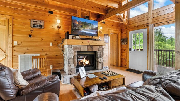 A cozy cabin interior with a stone fireplace, leather furniture, and a large TV screen. - Sweet Bearoline-Great Views, Game Roon, Close to Dollywood (Sevierville)