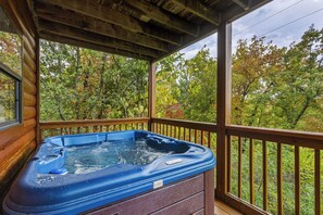 A hot tub on a wooden deck with a view of autumn trees.