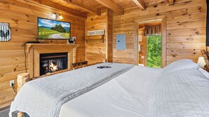 A cozy log cabin room with a bed, a fireplace, a television, and a sign that reads "FARM CHARM". - Sweet Bearoline-Great Views, Game Roon, Close to Dollywood (Sevierville)