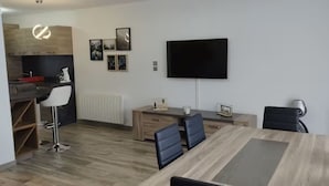 A modern kitchen with a built-in oven and microwave, a dining area with a wooden table and chairs, and a flat-screen TV mounted on the wall. - Between lake and mountains, L'ange des Cimes welcomes you to Savines-le-Lac (Savines-le-Lac)