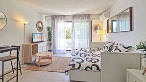 A modern hotel room with a bed, a desk, a chair, a small table, and a potted plant. - LX146 - Studio cosy avec balcon & vue mer - Monaco (Beausoleil)