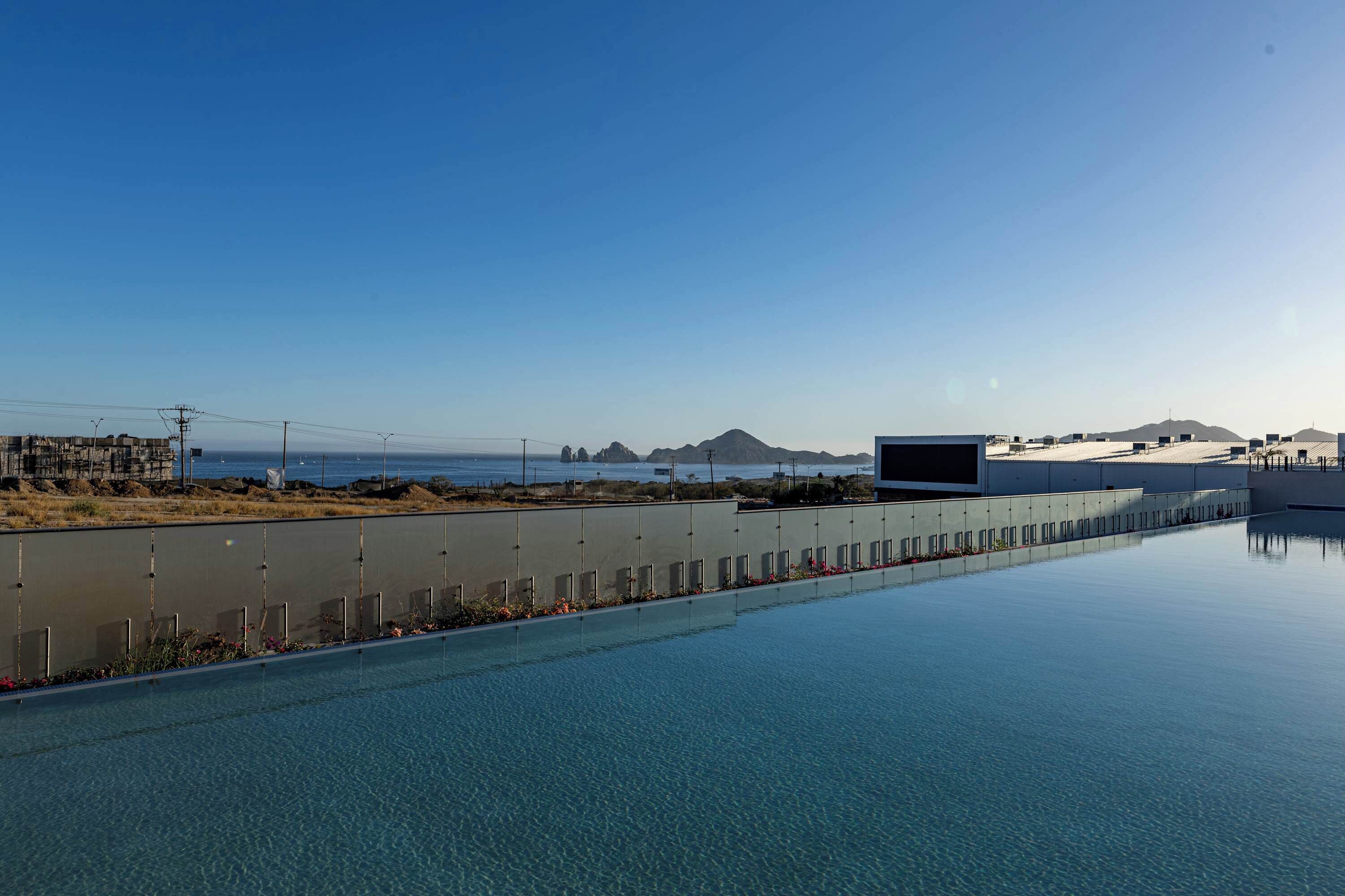 Una piscina amb aigua cristal·lina, vista a l'oceà i muntanyes a la llunà.