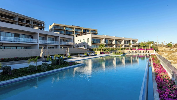 A hotel with a swimming pool, multiple balconies, and a landscaped garden.
