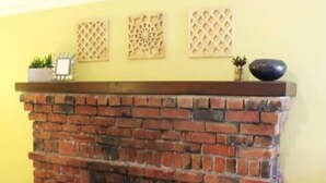 A brick fireplace with a mantel, a small shelf with decorative items, and a lattice wall decoration. - Roomy Studio Walkable to UC Berkeley w/parking (Berkeley)