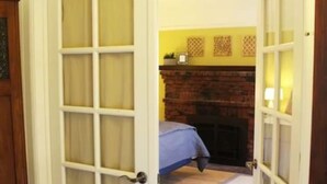 A room with a bed, a fireplace, and a door leading to another room. - Roomy Studio Walkable to UC Berkeley w/parking (Berkeley)