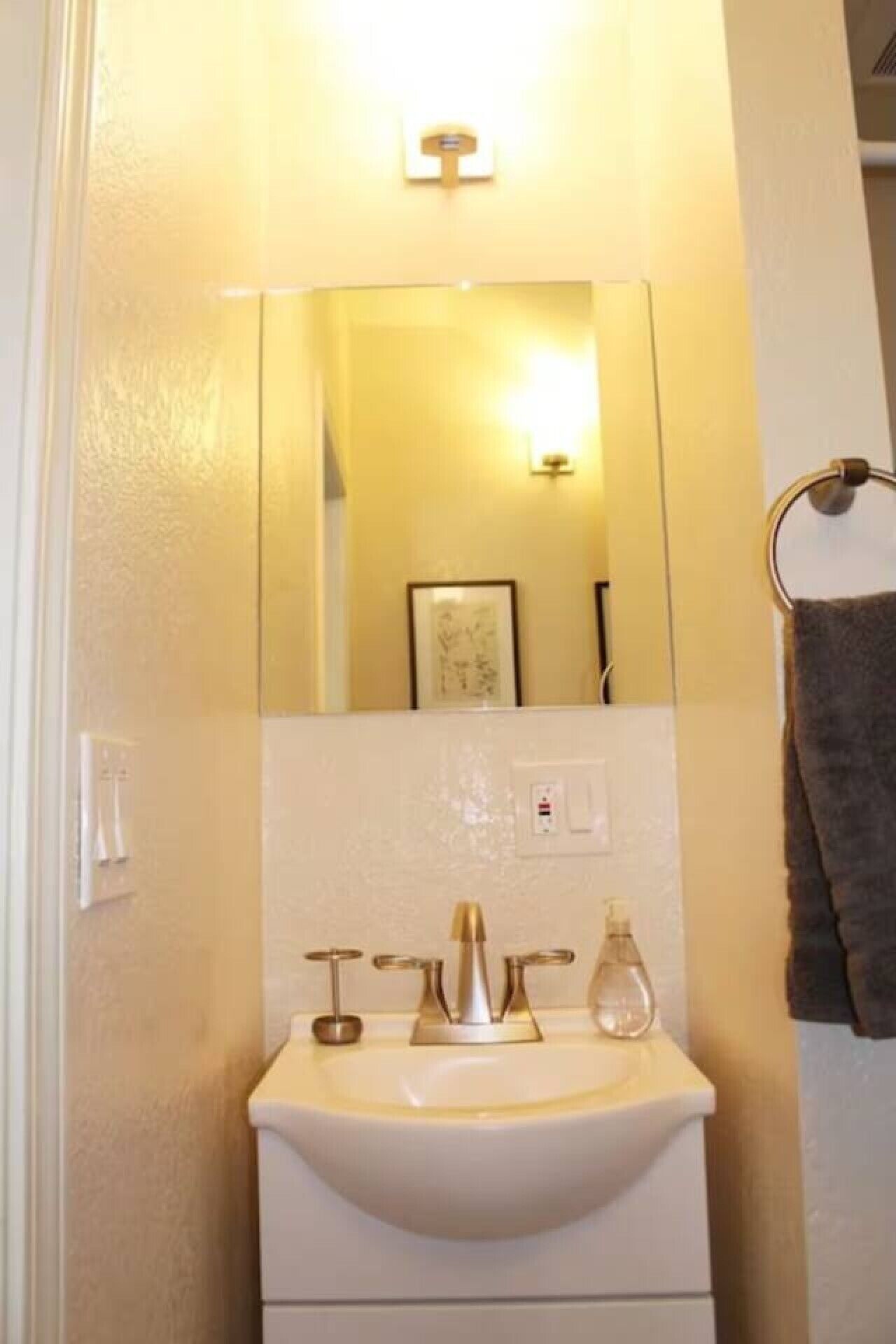 A bathroom with a white sink, a mirror, and a towel rack.