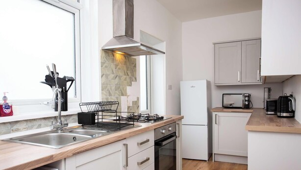 Una cocina moderna con estufa a gas, horno integrado, refrigerador y una ventana que proporciona luz natural.
