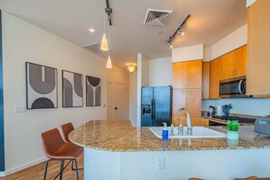 A modern kitchen with granite countertops, stainless steel appliances, and a central island with seating. - Upscale PHX Stay Pool,Gym,Balcony,WD,Parking (Phoenix)
