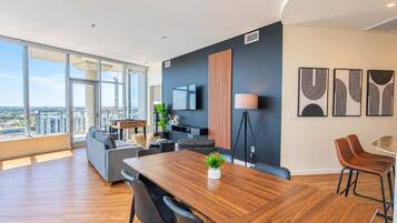 A modern living room with a large window, a wooden dining table, and a sofa.
