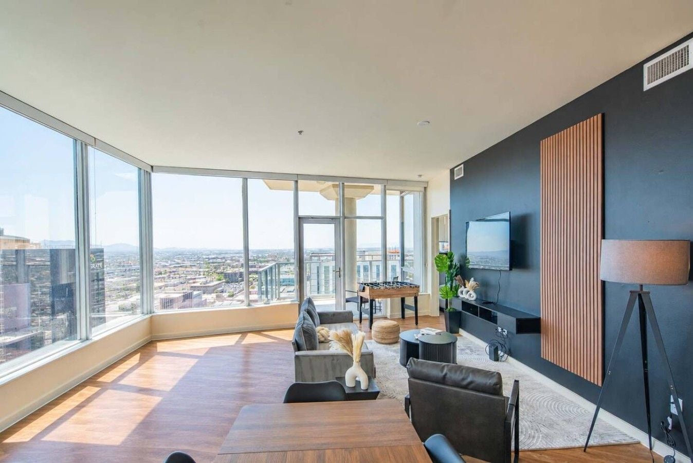 A spacious living room with a large window, a flat-screen TV mounted on the wall, and a foamy white sofa.