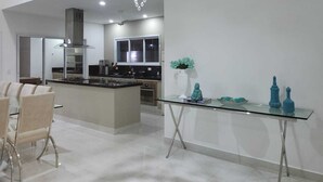 Une cuisine moderne dotée d’un îlot central, d’appareils électroménagers en acier inoxydable et d’un luminaire suspendu.