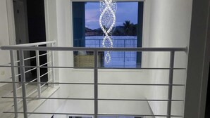Un intérieur moderne avec un escalier, un lustre et une vue sur l’extérieur.