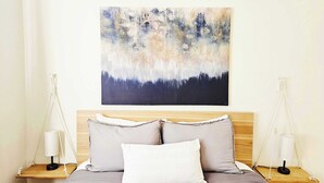 A bedroom with a bed, two bedside tables, and a wall-mounted abstract painting. - Seabright Breeze (Santa Cruz)