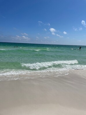 A beach with clear turquoise water, gentle waves, and a sandy shore.