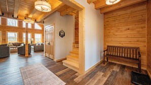A spacious wooden interior with a staircase, a bench, and a sofa area. - Spacious Lodge w/ Hot Tub, Fire Pit & Games (Swanton)