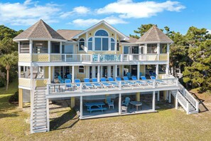 A multi-story house with a balcony, outdoor seating, and a covered patio area. - Sunny Side, Amazing Ocean Views, Large Groups - 759 Marlin (Fripp Island)