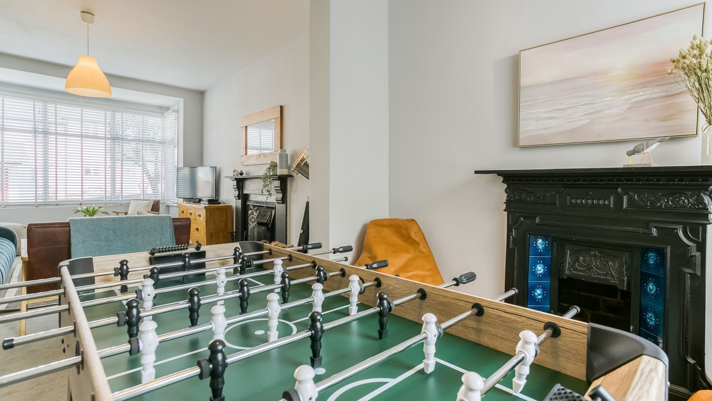 A room with a foosball table, a fireplace, a sofa, and a television.