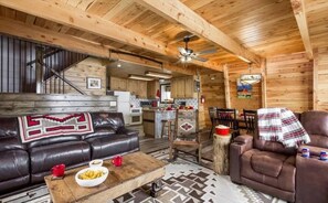 Un intérieur chaleureux de chalet en bois, avec un canapé en cuir, une table basse et un coin repas.