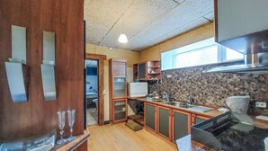 A kitchen with wooden cabinets, a stone backsplash, and a window providing natural light. - Gorgeous apartment in åsljunga (Åsljunga)