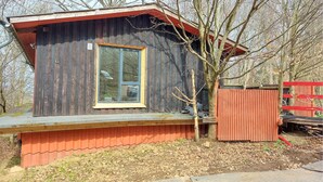 A small wooden cabin with a single window, a red roof, and a fenced yard. - Cozy apartment in åsljunga with sauna (Åsljunga)