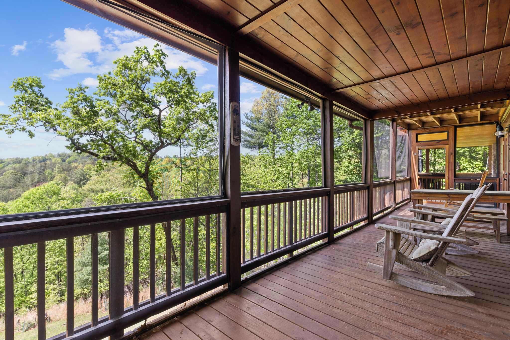 A wooden deck with a view of a forest and a lake.