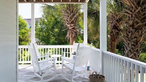 A wooden porch with white rocking chairs and a wicker basket. - Steele Away - 4 Bedrooms, 3.5 Baths, Private Pool, Emerald Isle (Emerald Isle)