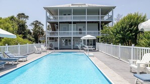 A two-story building with a pool, white railings, and lounge chairs. - Steele Away - 4 Bedrooms, 3.5 Baths, Private Pool, Emerald Isle (Emerald Isle)