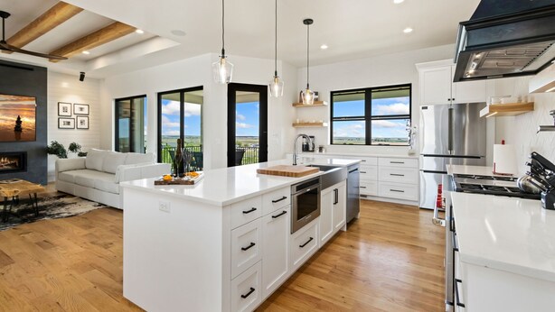 A modern kitchen with white cabinetry, stainless steel appliances, and large windows offering a view of the outdoors. - Bridle Ridge Retreat | Modern Comfort, Open Views (Severance)