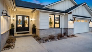 A modern two-story house with a front porch, a garage, and a well-lit entrance. - Bridle Ridge Retreat | Modern Comfort, Open Views (Severance)