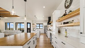 A modern kitchen with white cabinetry, wooden countertops, and pendant lighting. - Bridle Ridge Retreat | Modern Comfort, Open Views (Severance)