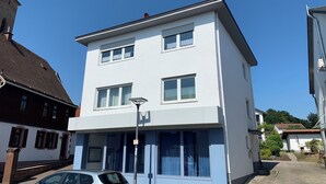 A two-story building with a flat roof, large windows, and a visible street lamp. - Vacation apartment Klaus (Clausen)