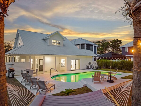 A house with a swimming pool, outdoor seating, and a hammock.