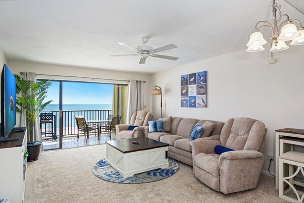 A living room with a large window, a ceiling fan, a coffee table, and a sofa. - 🌊Beach Front with Great Views-Pool+Hot Tub-Pelican Watch #602🌊 (Fort Myers Beach)