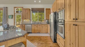Une cuisine moderne avec des armoires en bois, des appareils en acier inoxydable et un grand îlot central.