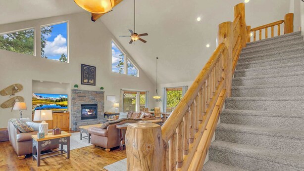 Un salon spacieux doté d’une cheminée, de parquets en bois et d’un escalier avec une rampe en bois.