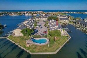 Vue aérienne d’une marina avec des bateaux amarrés, une piscine et des immeubles résidentiels.